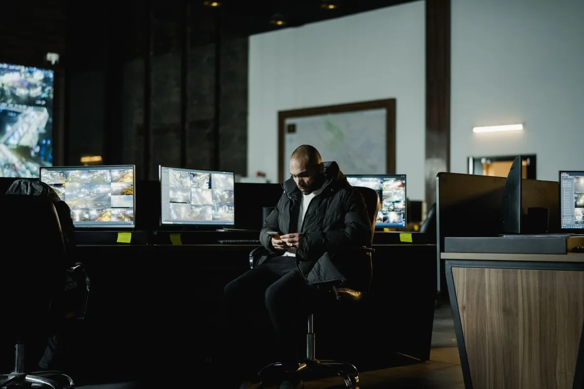 A security professional inspecting electronic equipment in a corporate meeting room as part of a workplace security review.