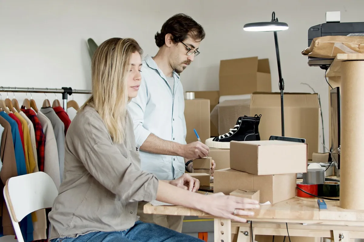 A small business owner reviewing financial records and customer orders at a desk.