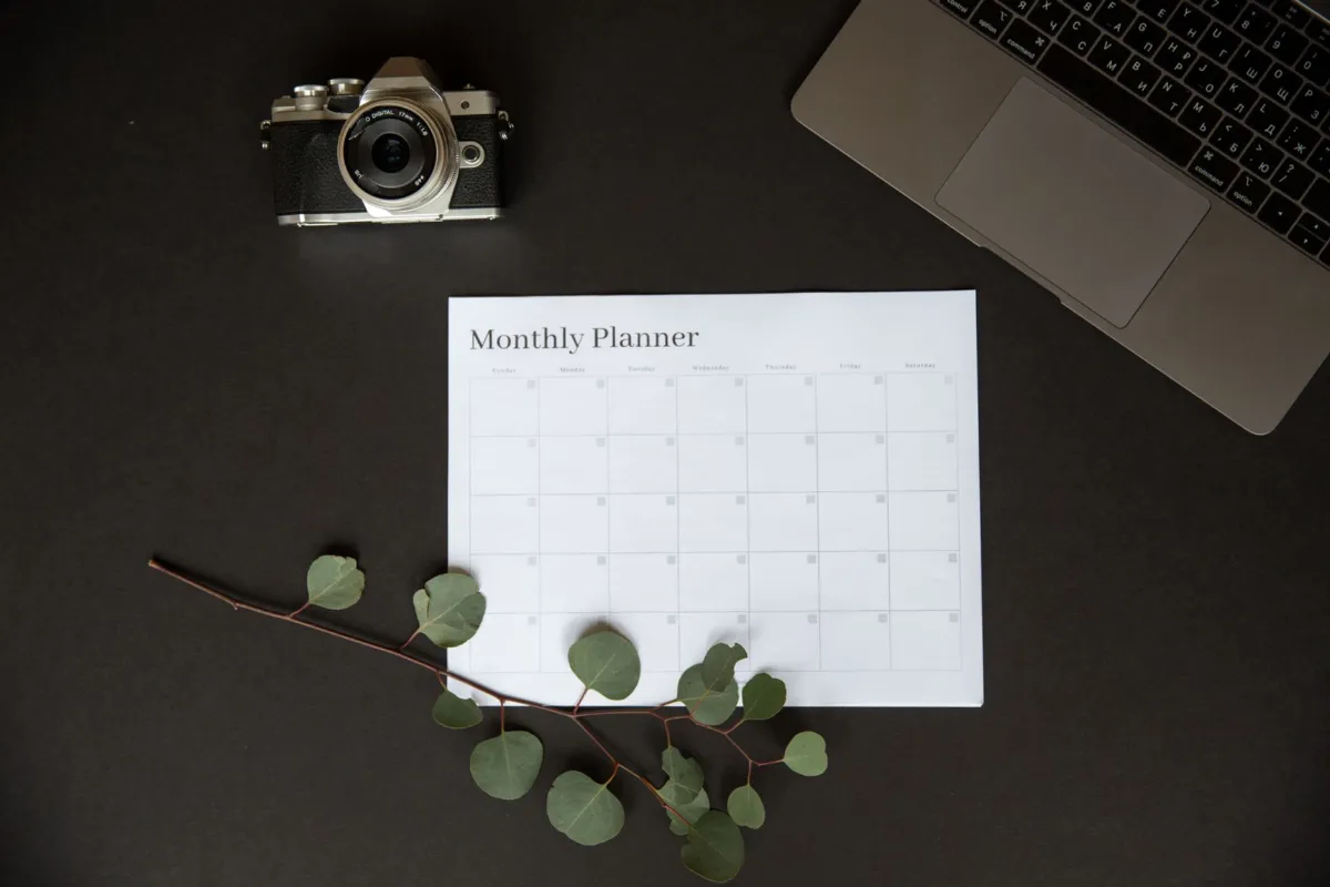 A wall calendar hanging above a tidy office desk with a laptop.